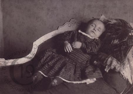 An infant laid out on a sofa