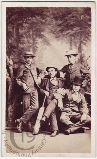 Four men with a cricket bat