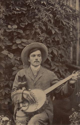 A young man with a banjo and a kitten
