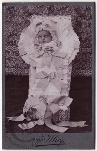 Baby in coffin with ribbons